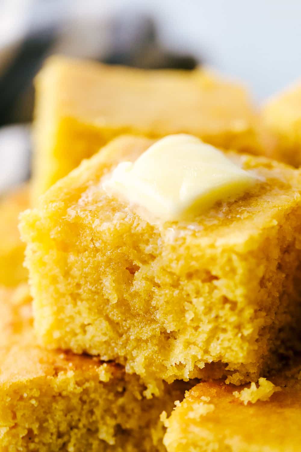 A closeup of a slice of cornbread with butter on top. 