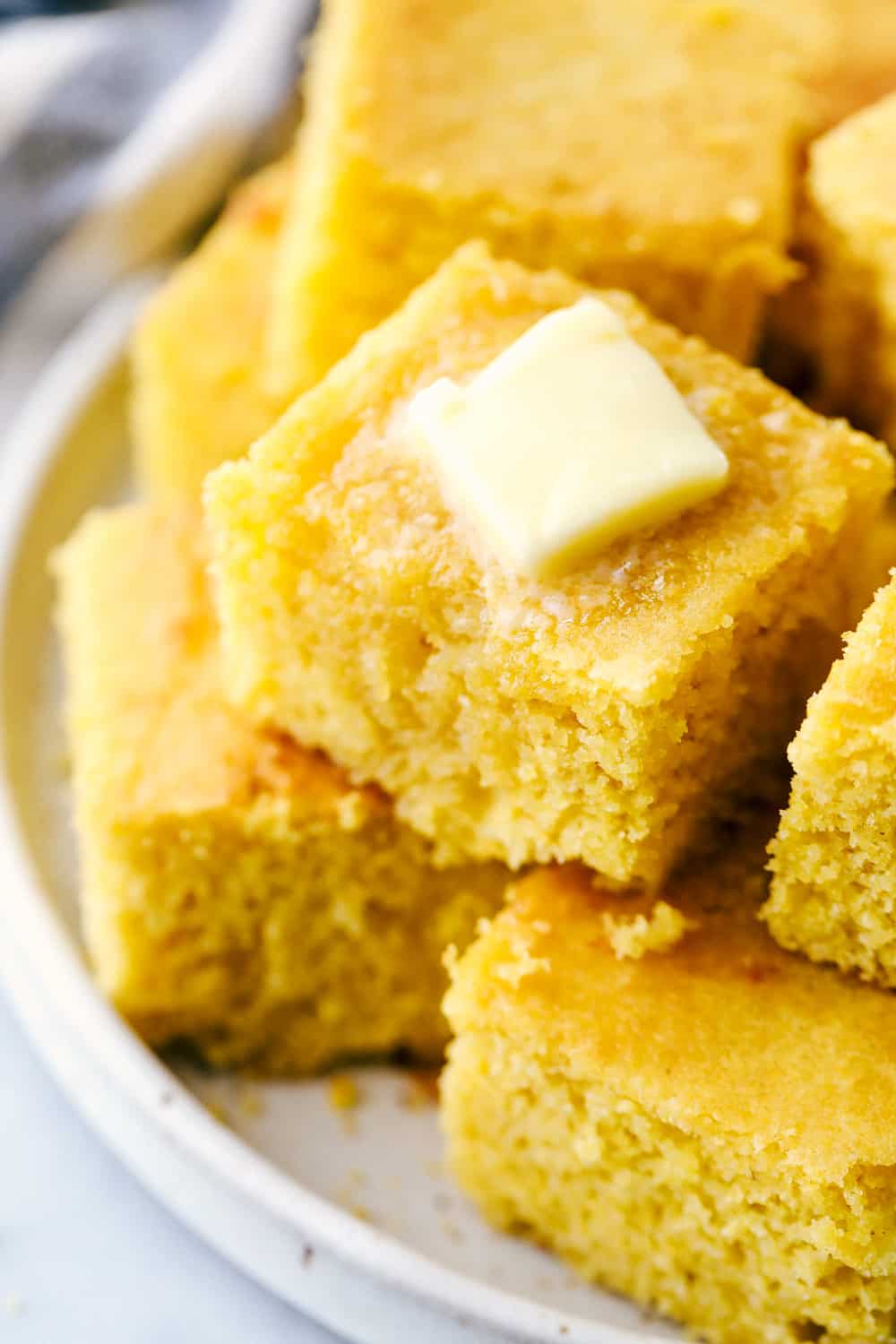 A stack of cornbread with a slice of butter melting on top. 
