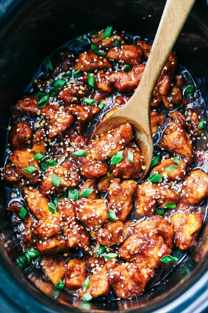 Slow cooker General Tso's chicken in a slow cooker with a wooden spoon.