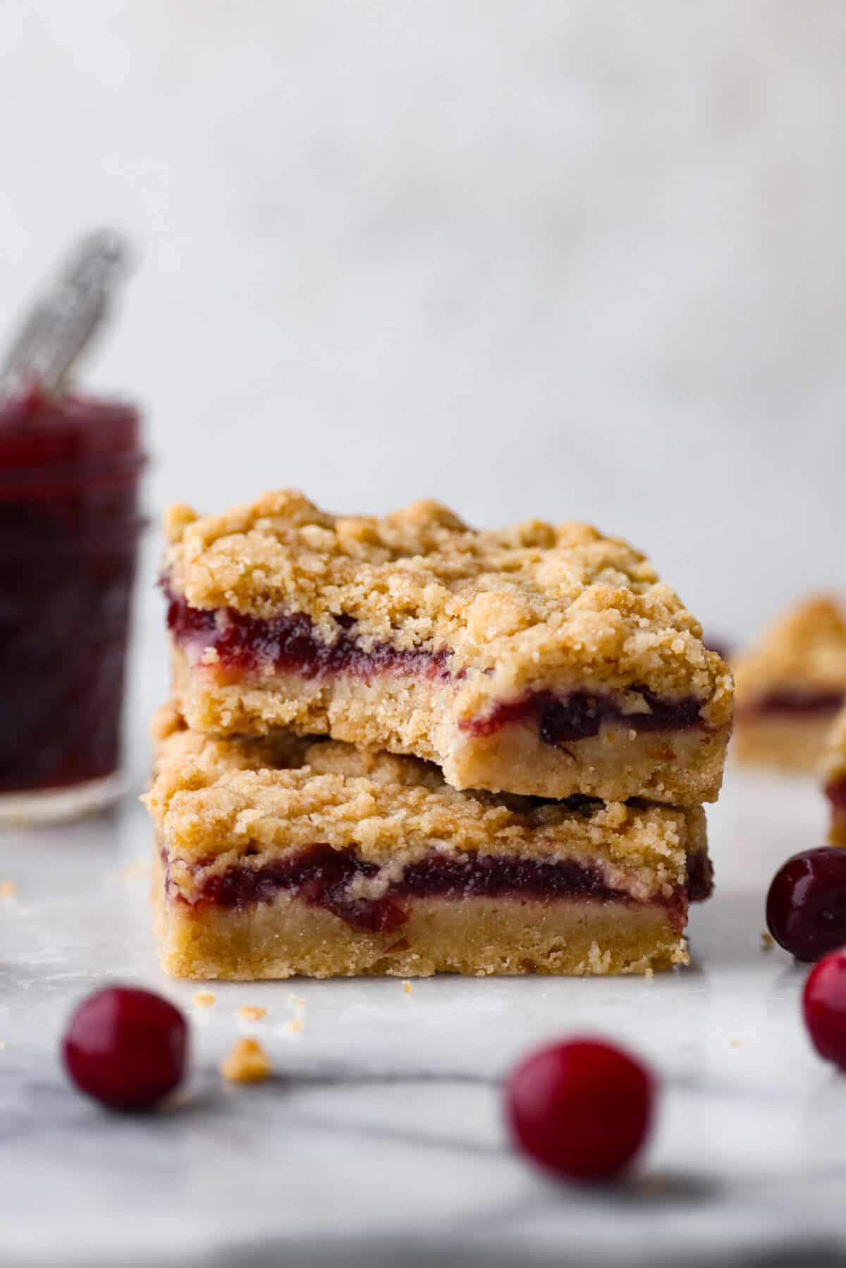 2 cranberry bars stacked on top of each other. One has a bite taken out of it.