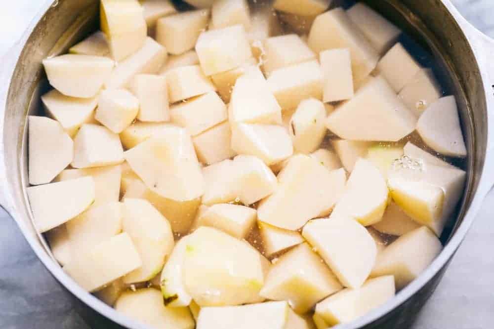 A sauce pan full of water with potatoes chopped into 1 inch pieces. 
