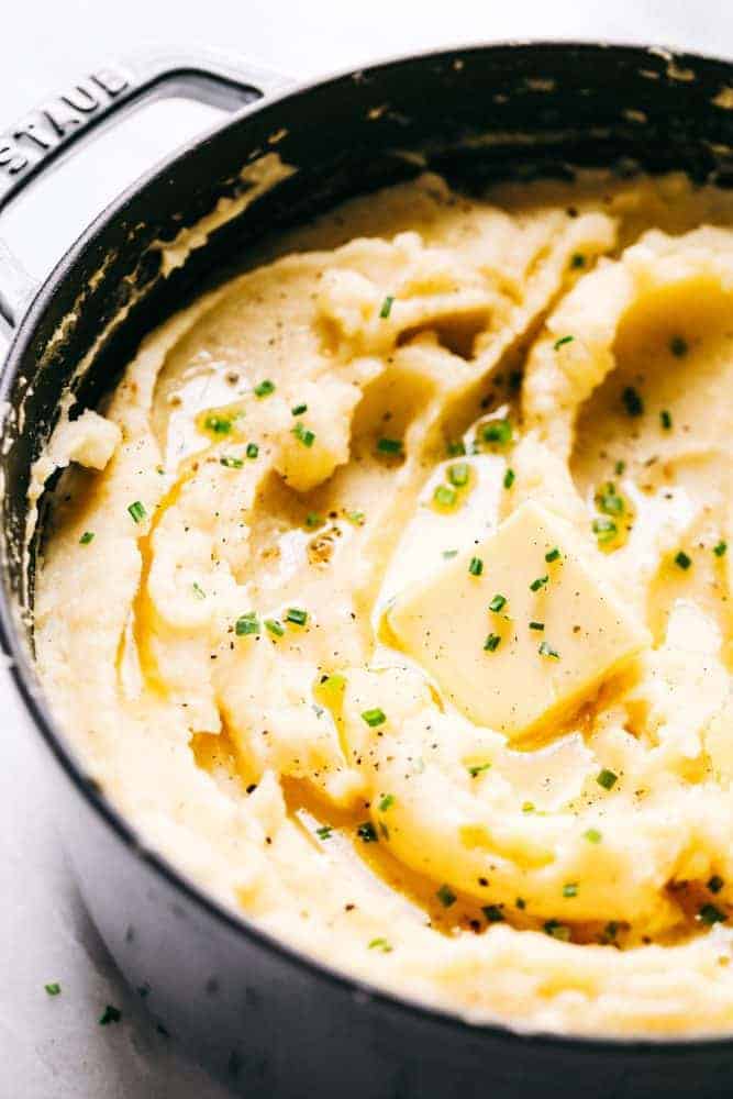 Dad's Famous Mashed Potatoes in a Staub sauce pan with a slice a butter over top.