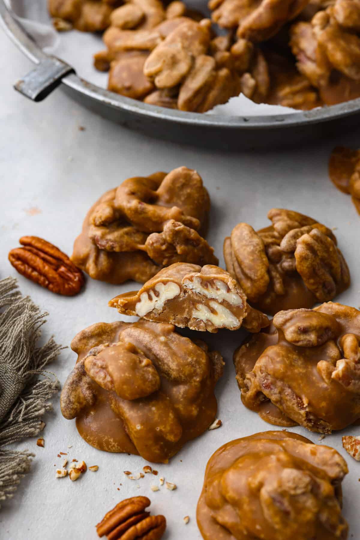 Pecan pralines on parchment paper. One cut in half so that you can see the pecans inside. 