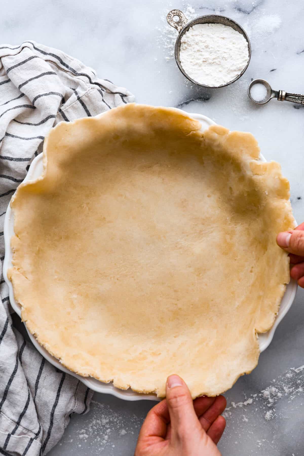 A pie crust being put into a pan. 
