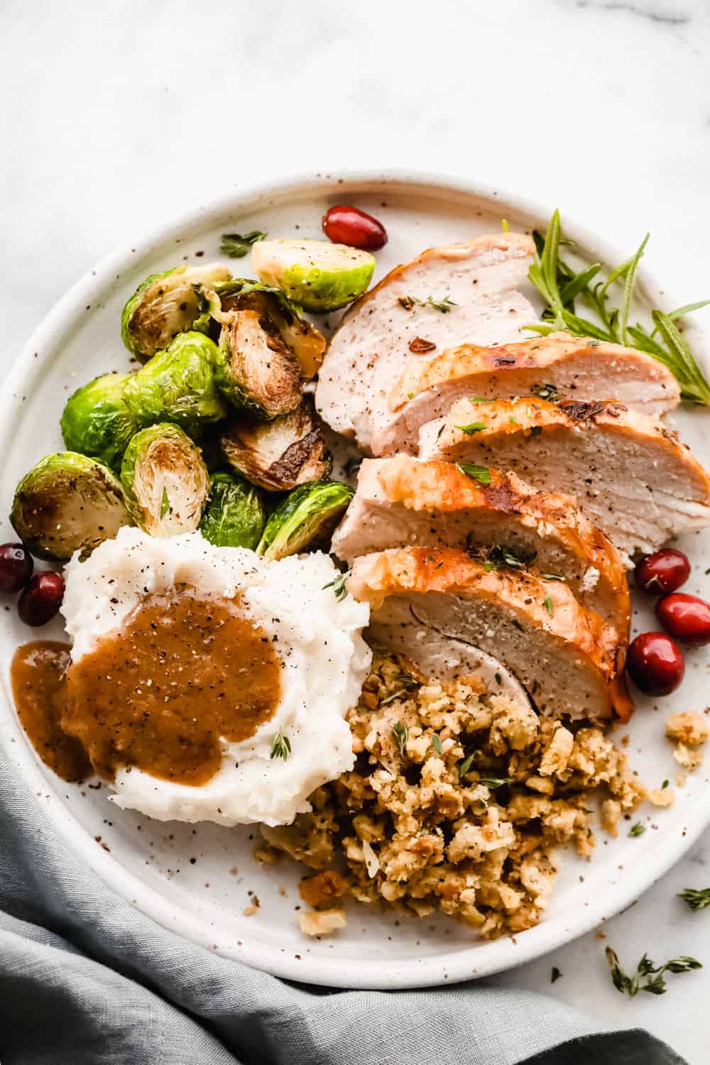 Sliced turkey, mashed potatoes with turkey gravy, brussel sprouts and pilaf all plated together.