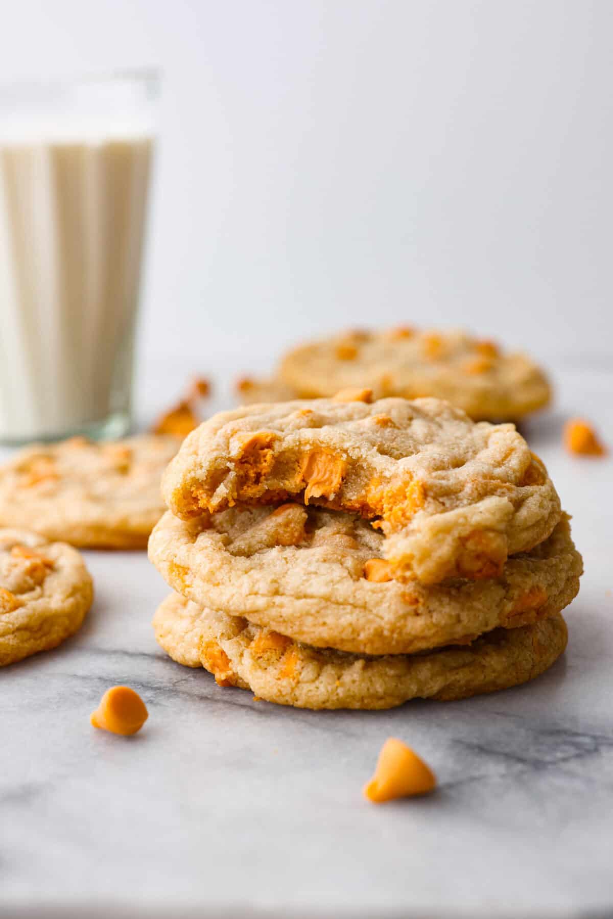 A stack of butterscotch cookies with a bite taken out of the top one. 