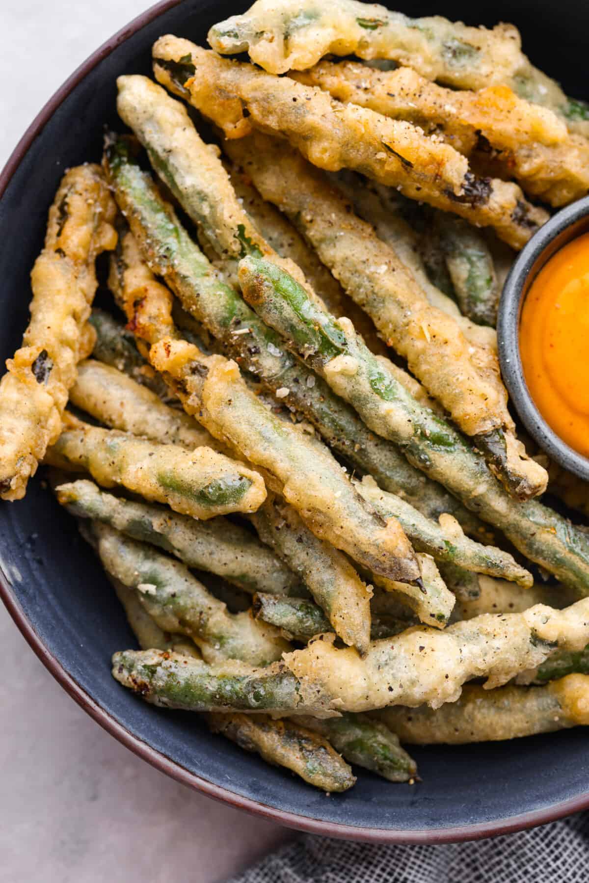A close up of the crispy friend green beans on a platter. 