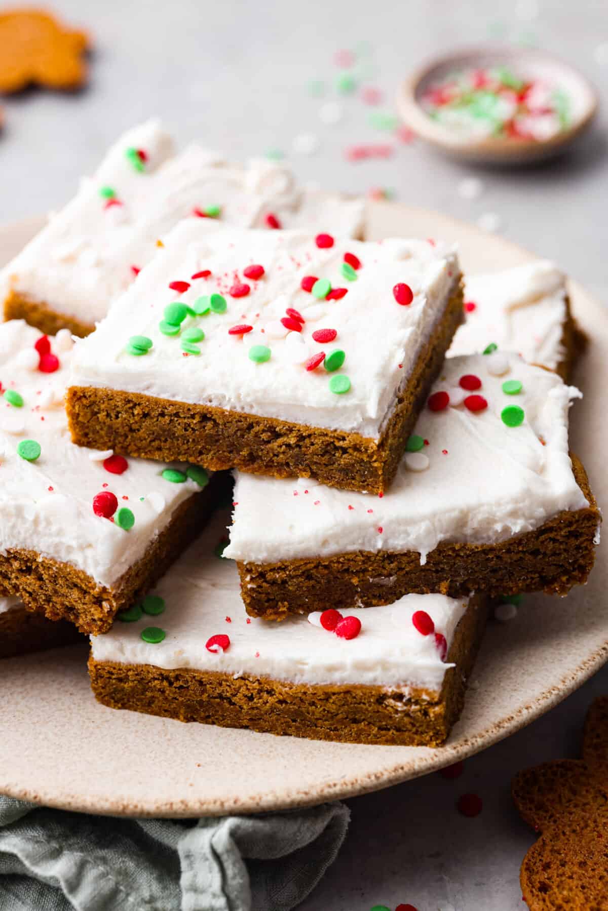 Close view of gingerbread sugar cookie bars stacked on a plate with sprinkles.