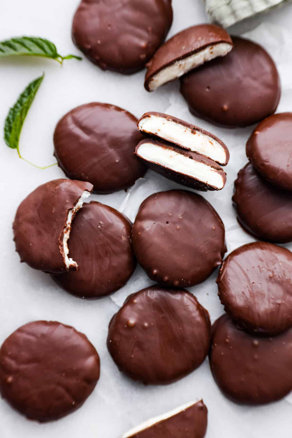 Top-down view of peppermint patties. Some are broken in half so the mint filling can be seen.