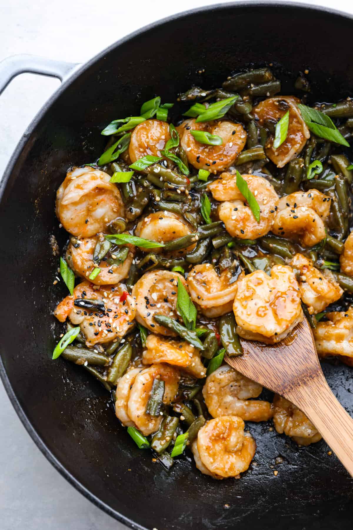Cooked Hunan shrimp and green beans in a black skillet.