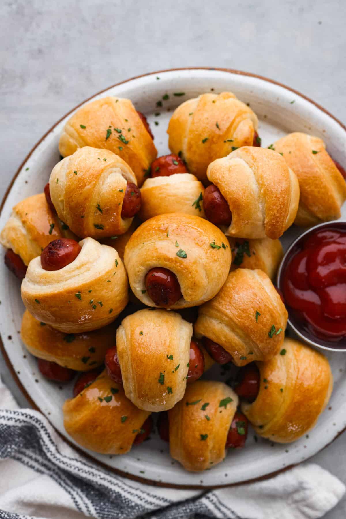 Top-down view of pigs in a blanket served with ketchup.