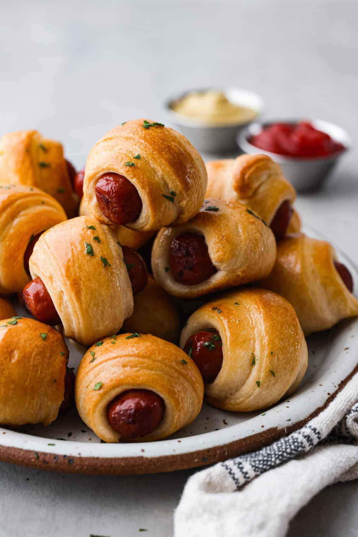 A stack of pigs in a blanket on a stoneware plate.