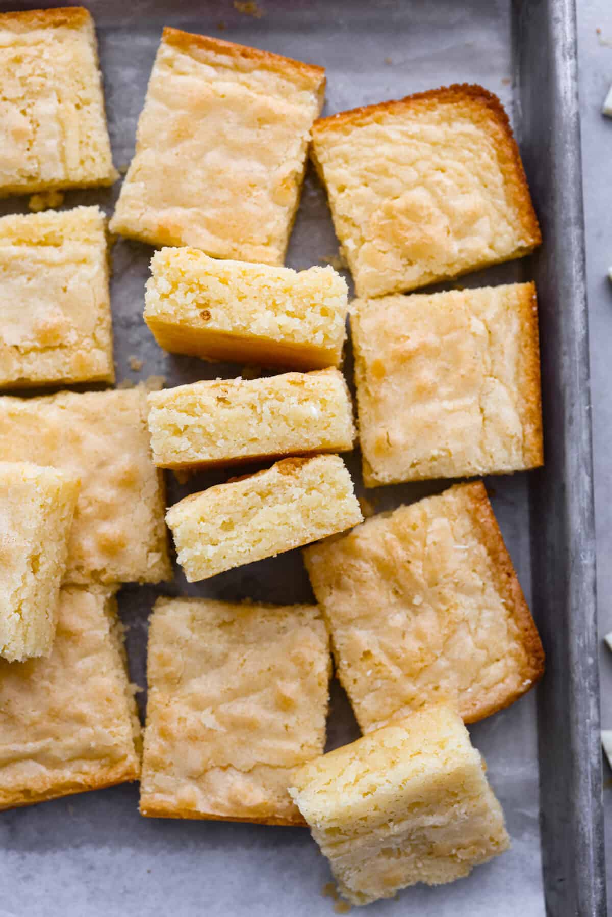 Top-down view of white chocolate brownies in a metal pan, cut into squares.