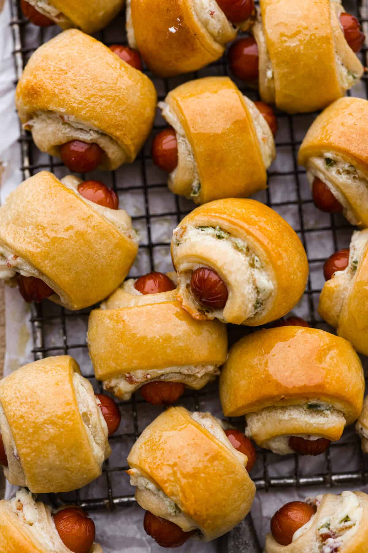 Close view of pigs in a blanket close together on a cooling rack.
