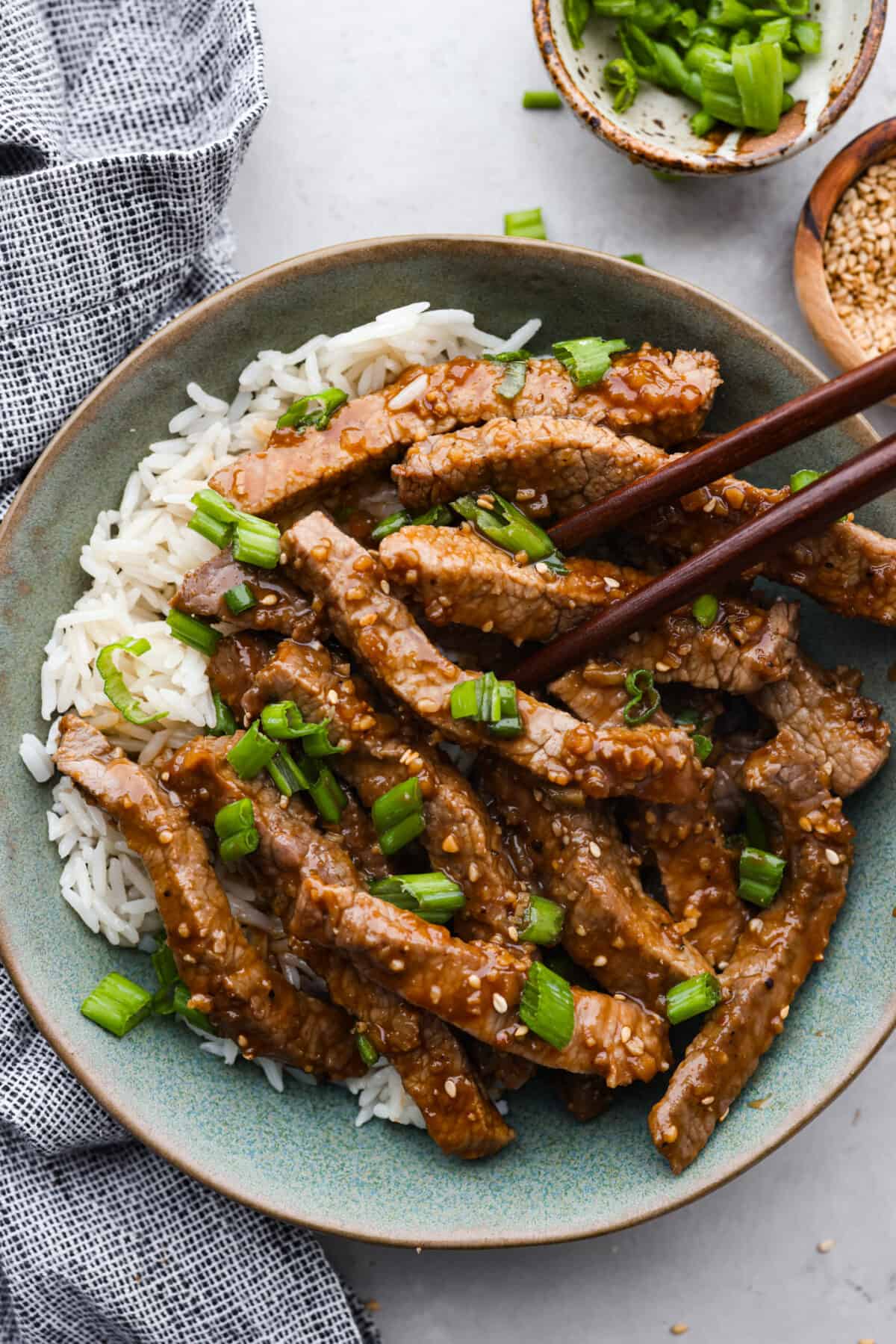 Korean beef bulgogi served over white rice in a stoneware bowl.