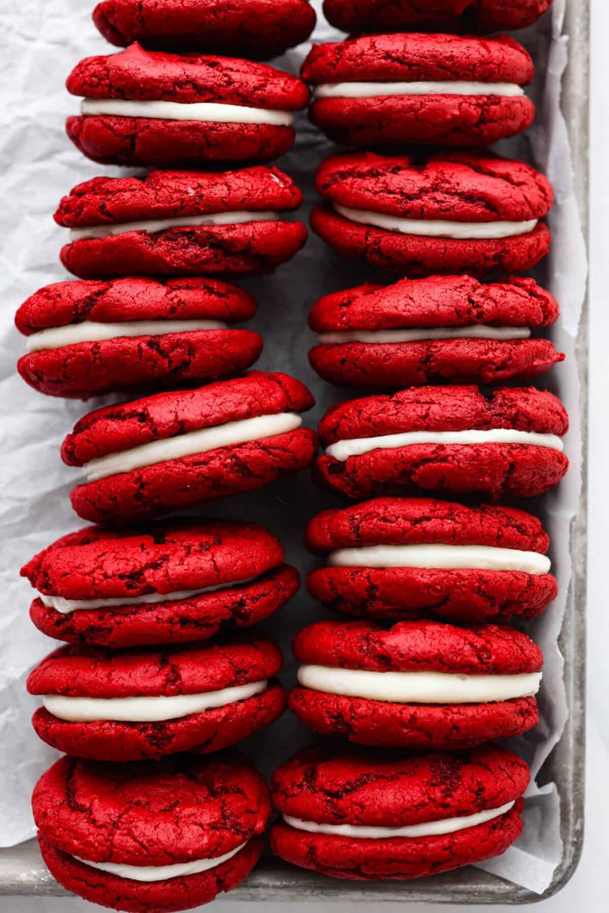Overhead view of red velvet Oreos on a baking sheet pan lined with parchment paper.