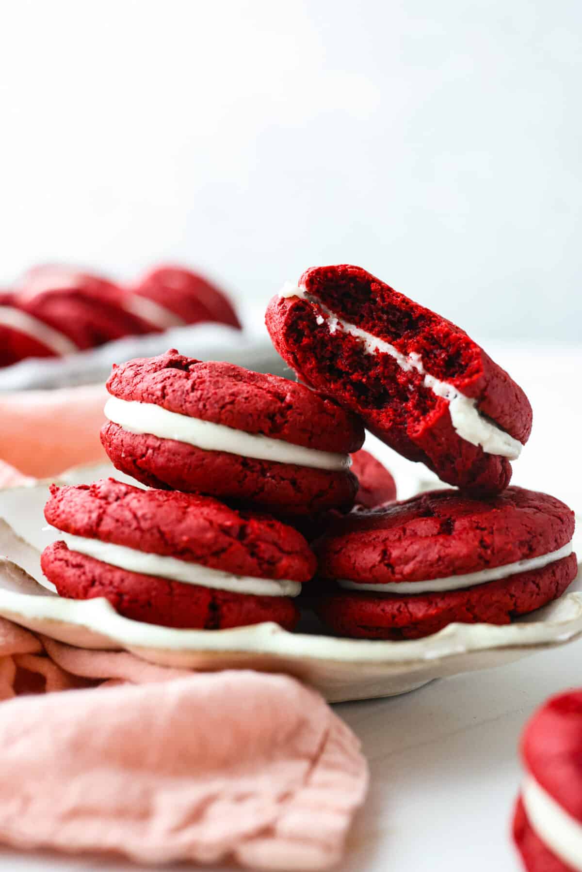 Close view of red velvet Oreos on a plate with a bite out of one of the cookies.
