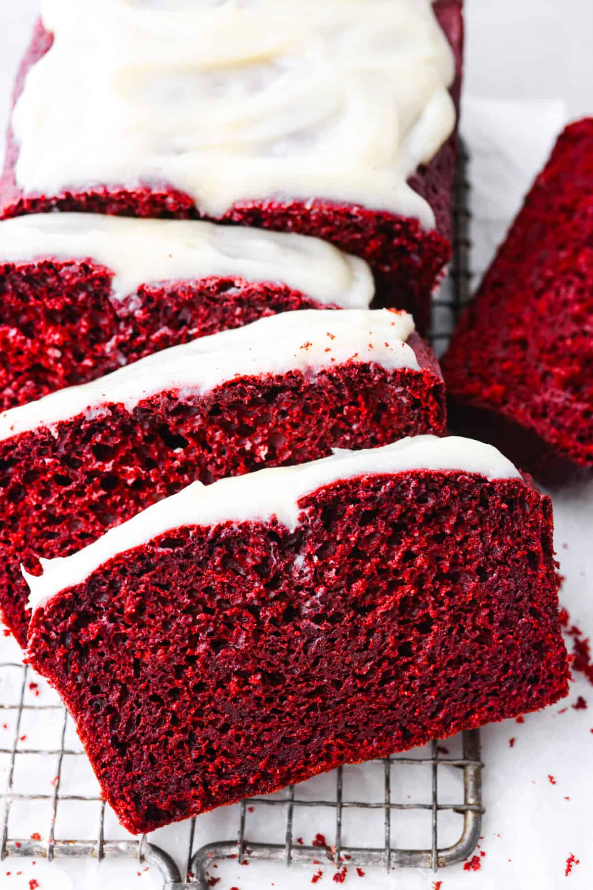 Close view of red velvet pound cake sliced with cream cheese glaze on top.
