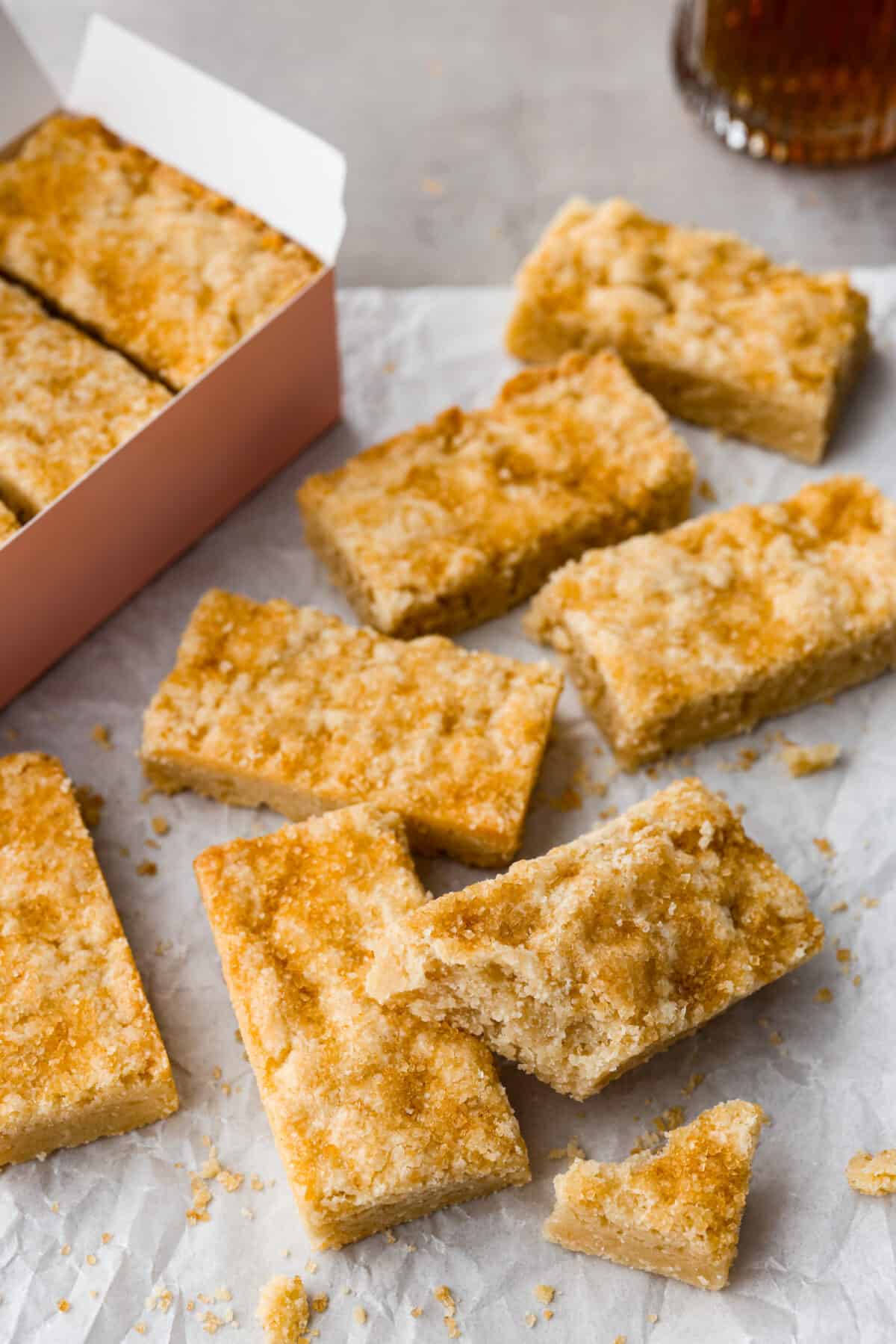 Biscuits (cookies) cut into rectangles on parchment paper with a pink box next to them filled with the cookies. 