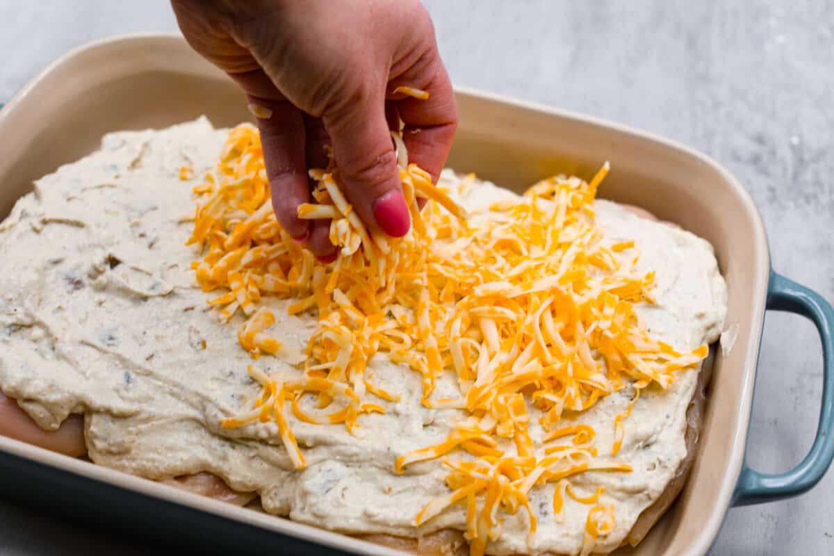 Sprinkling shredded cheese over the green chile chicken.