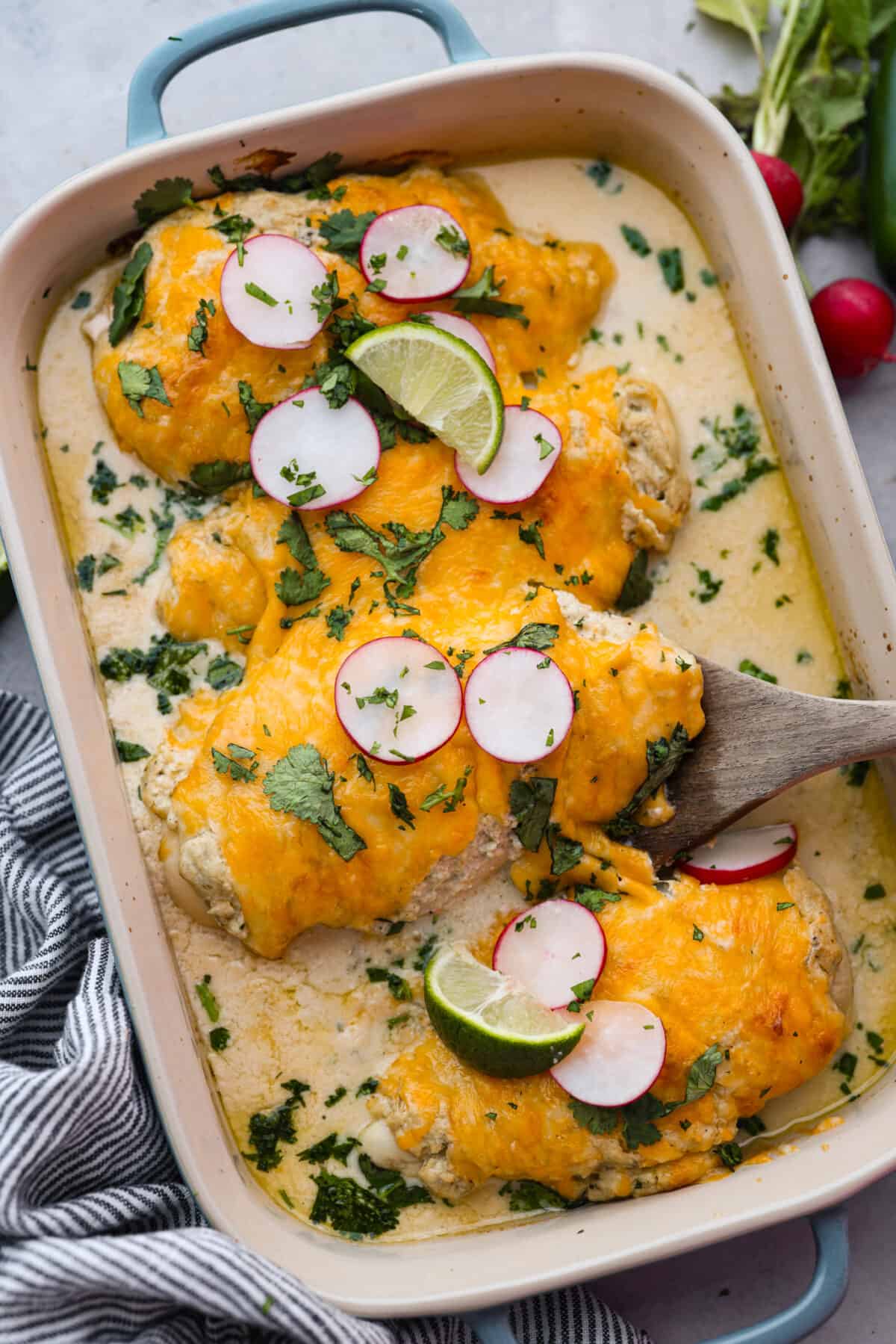 3 cooked pieces of chicken topped with cheese and a green chile cream cheese mixture.