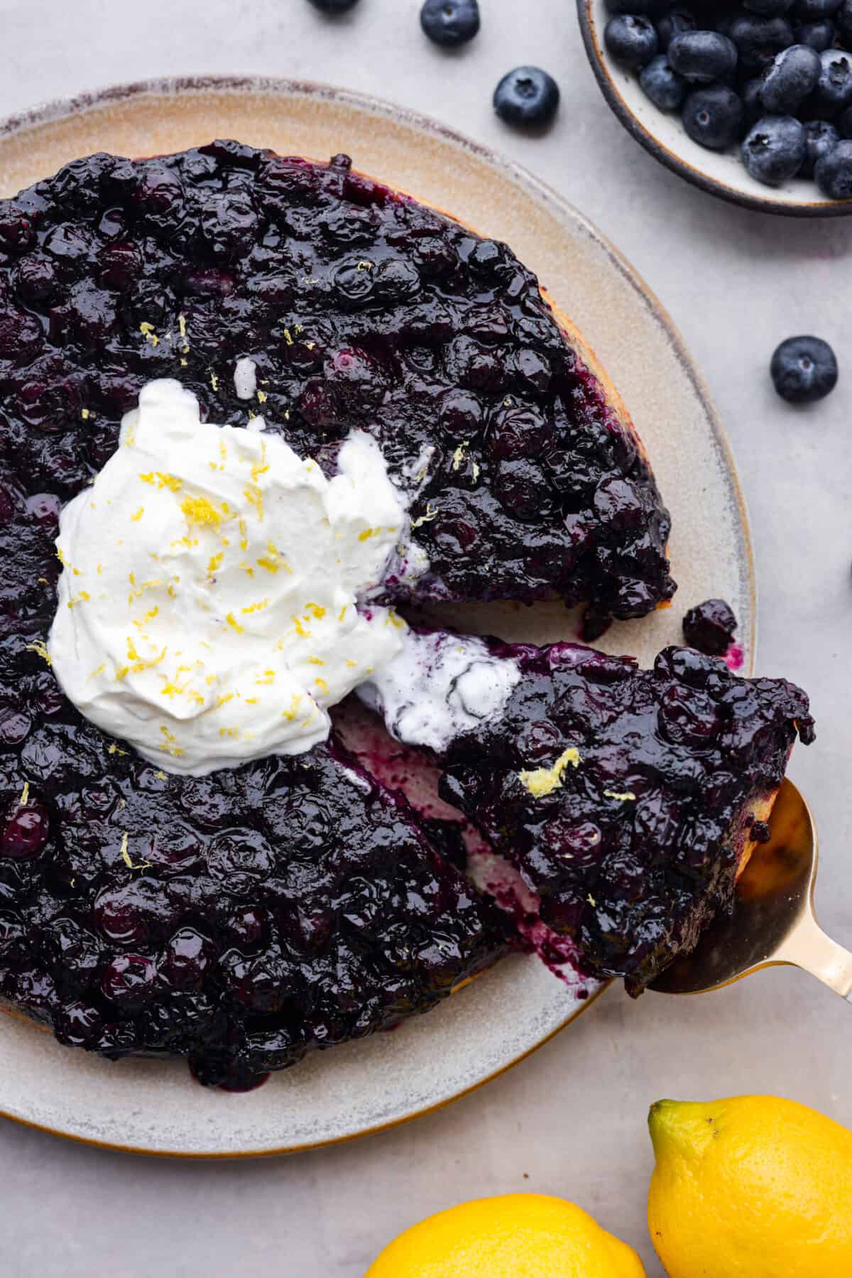 Top view of blueberry lemon upside-down cake on a platter with whipped cream.