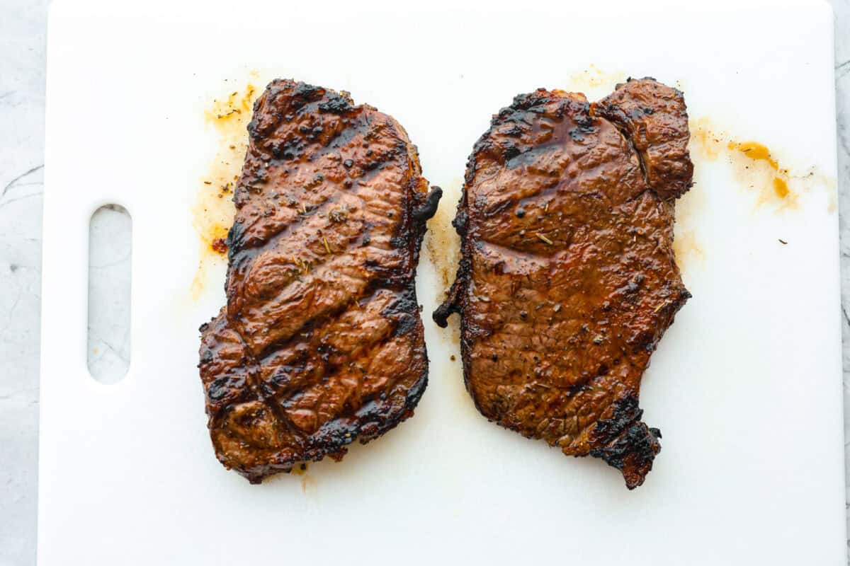 Third photo of two steaks resting before slicing.