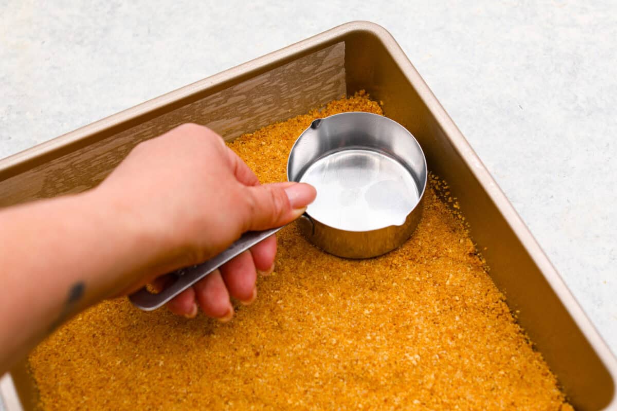 Second photo of the crust being pressed into a pan.