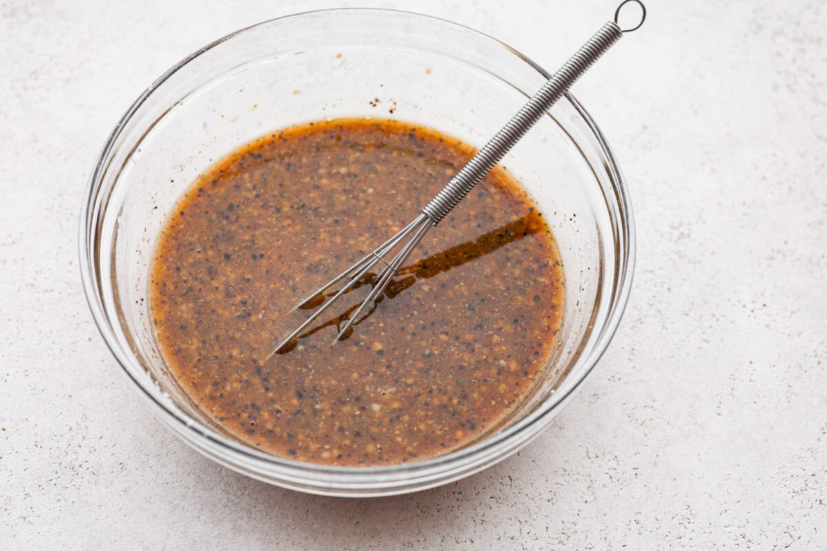 Overhead shot of a bowl and whisk with sauce ingredients mixed together.