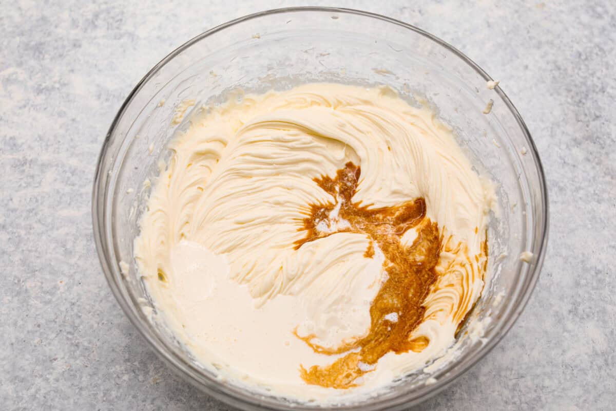 Overhead shot of cheesecake filling mixture with vanilla extract poured on it. 