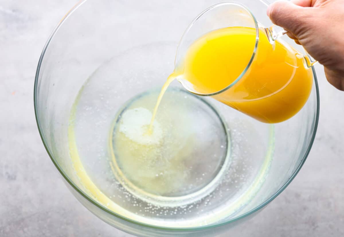 Overhead shot of pineapple juice being poured into a large bowl that already has Sprite in it.