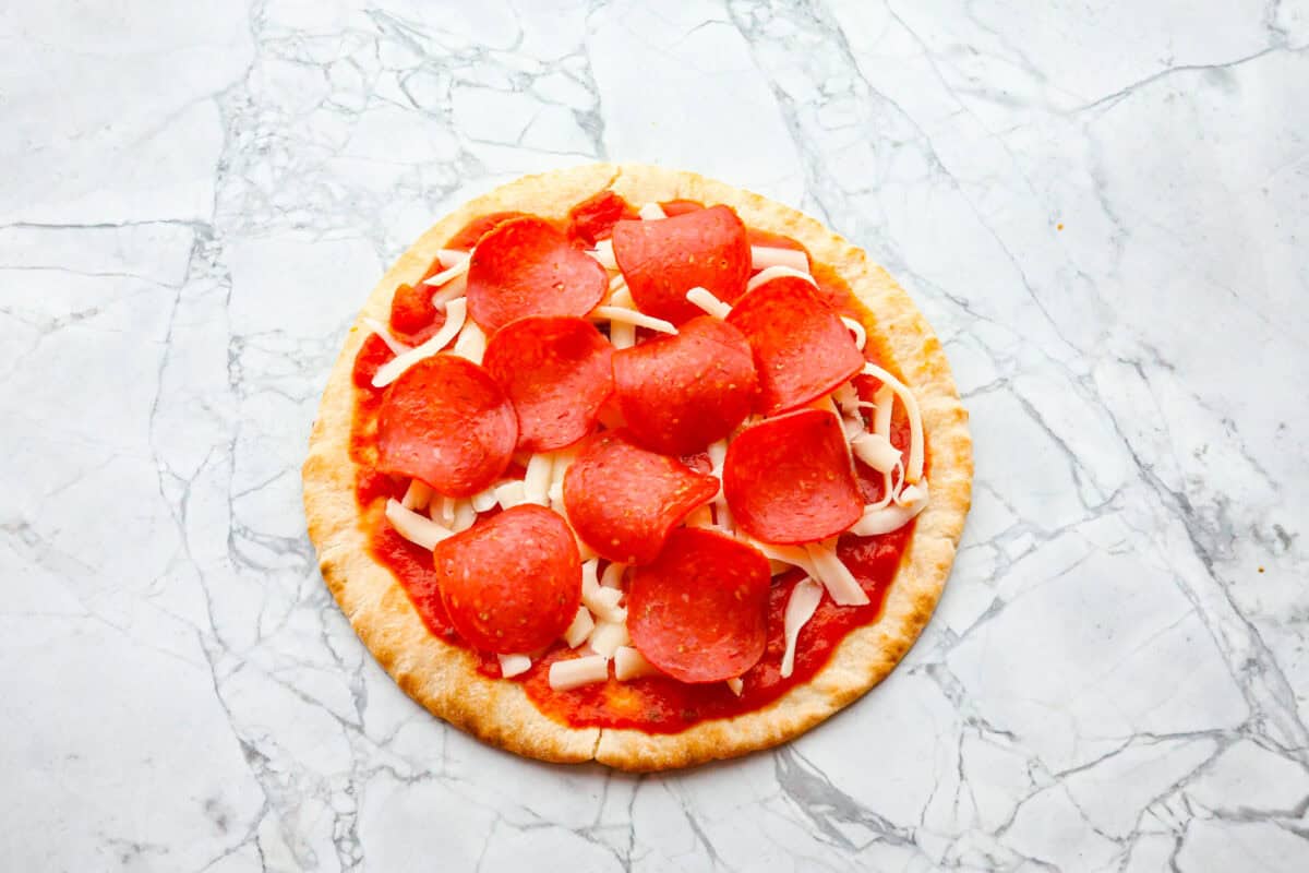 Overhead shot of pita with marinara, cheese and pepperoni. 