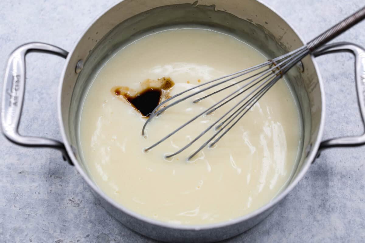 Overhead shot of cooked pie filling in pot with vanilla extract in it. 