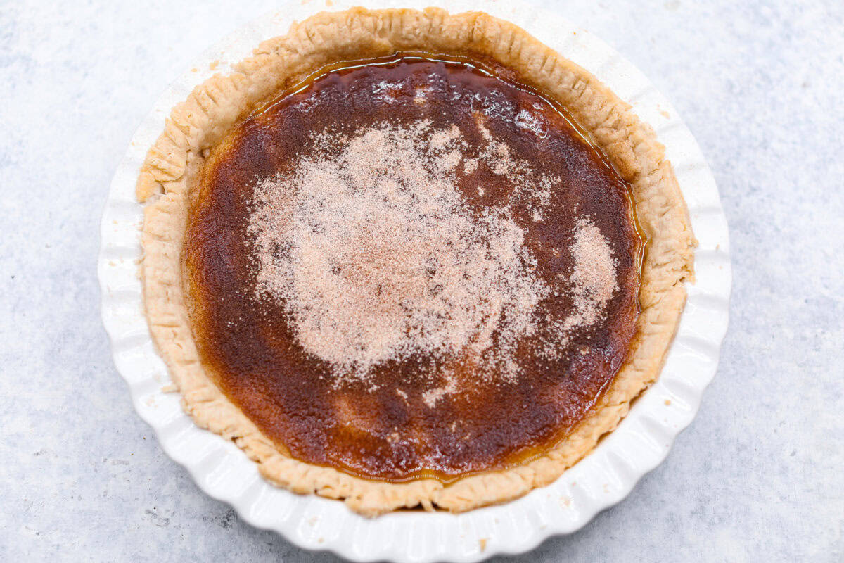 Overhead shot of pie before it has been placed in the oven with cinnamon sugar mixture over the top. 