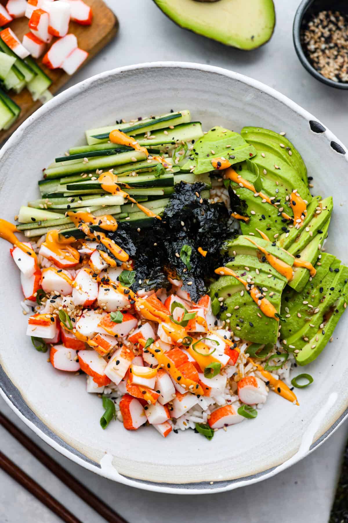 Overhead shot of plated sushi bowl with sauce green onions and sesame seeds. 