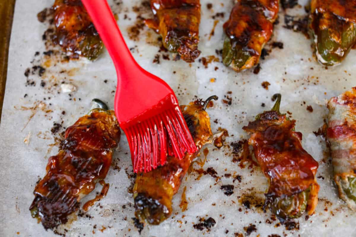 Angle shot of someone brushing bbq sauce on cooked Texas Twinkie's. 