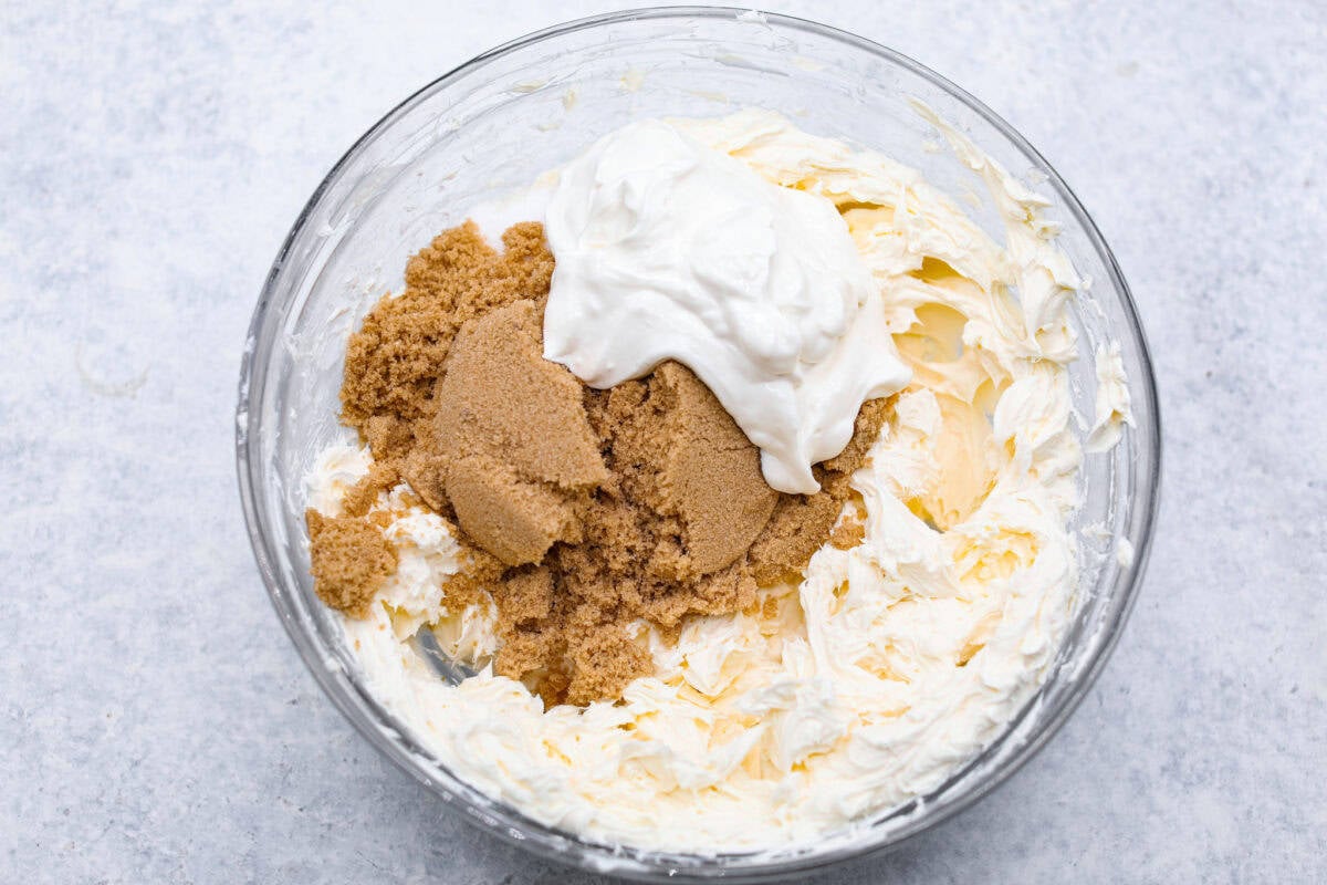 Overhead shot of brown sugar, cream cheese, and sour cream in glass bowl. 