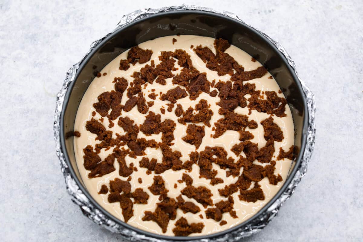 Overhead shot of cream cheese filling with bits of cinnamon sugar mixtures over the top in the springform pan. 