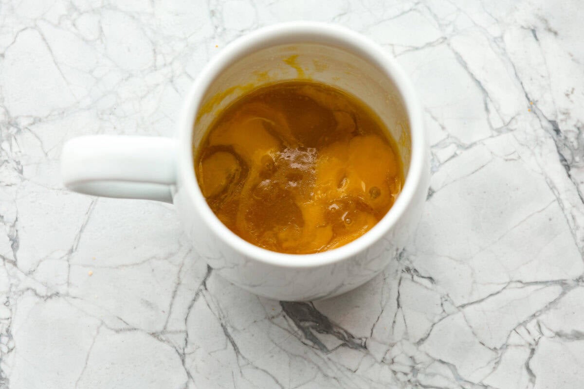 Overhead shot of sugars, egg yolk and butter mixed in a mug. 