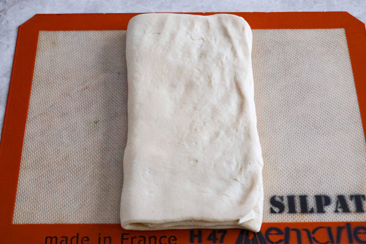 Overhead shot of croissant bread dough folded in thirds. 