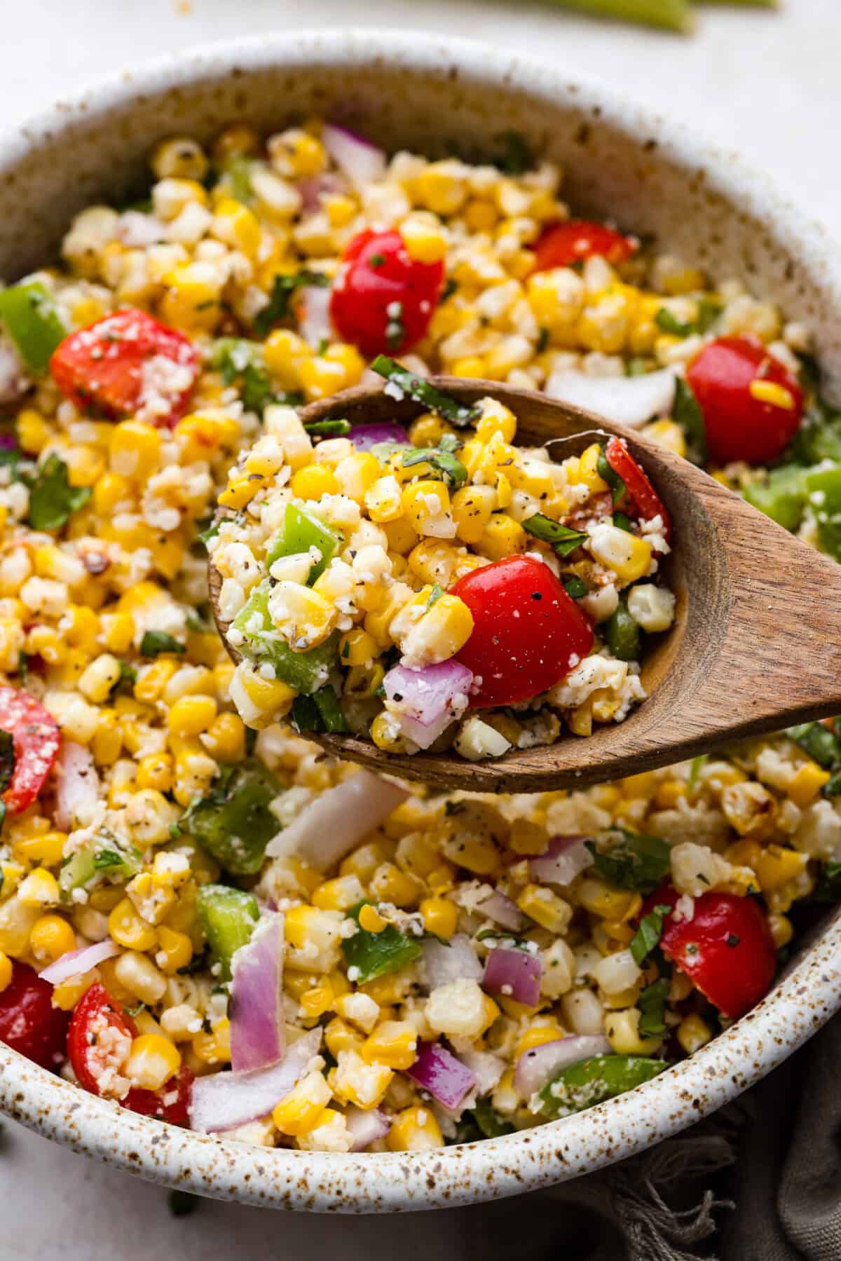 Angle shot of wooden spoon with scoop of Italian corn salad. 