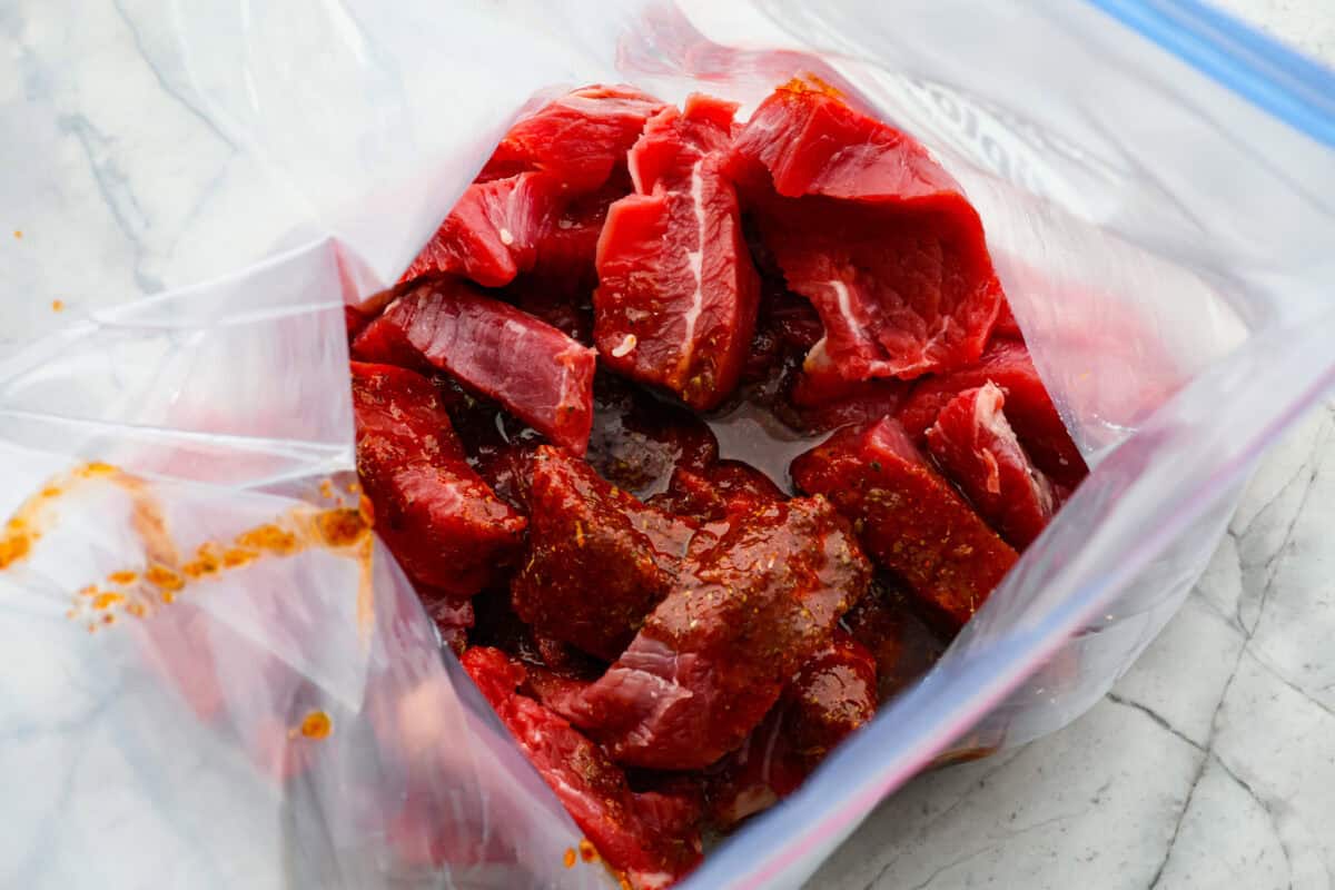 Overhead shot of sliced meat in bag with marinade poured over it. 