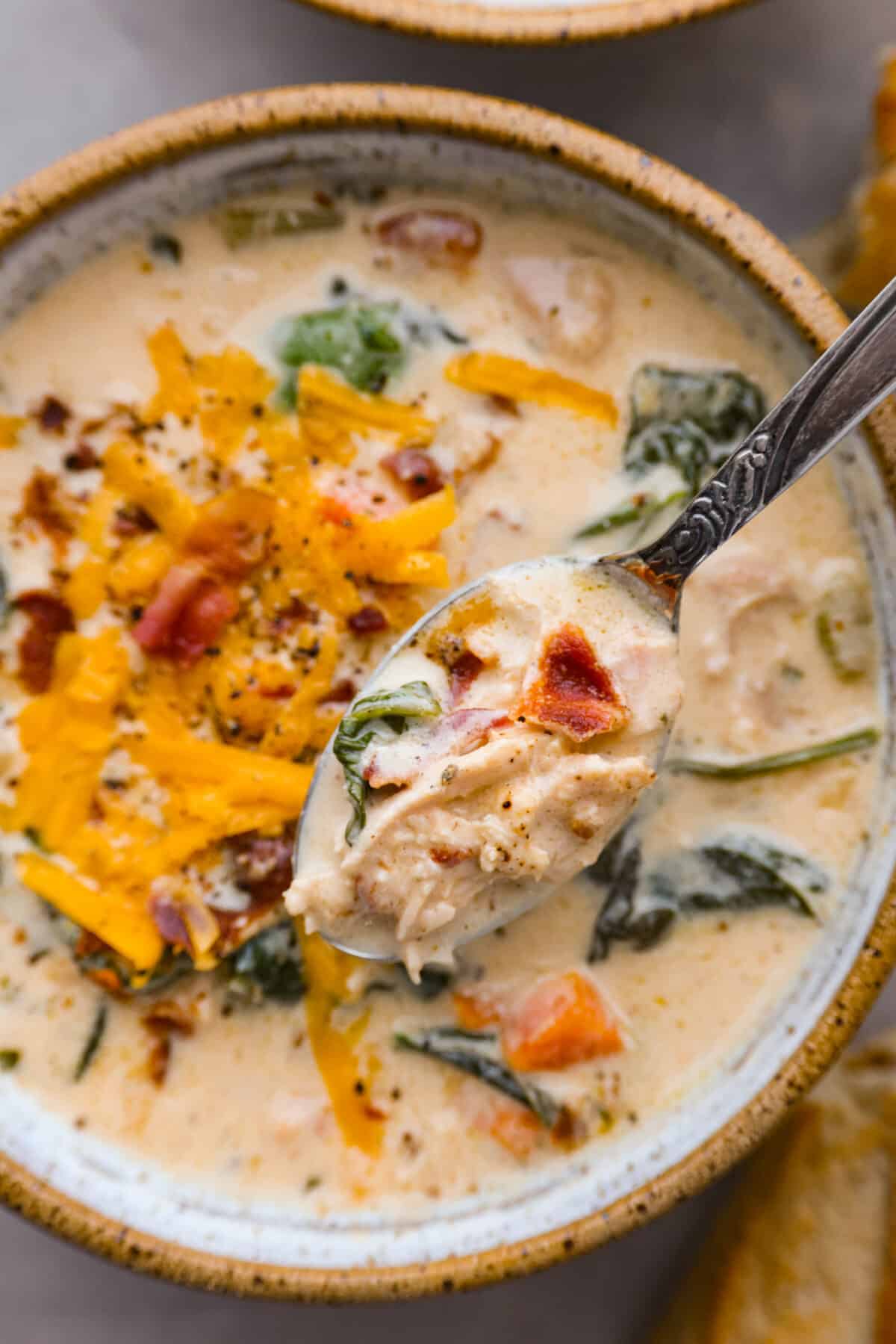 Top view of a spoon lifting soup out of a bowl.