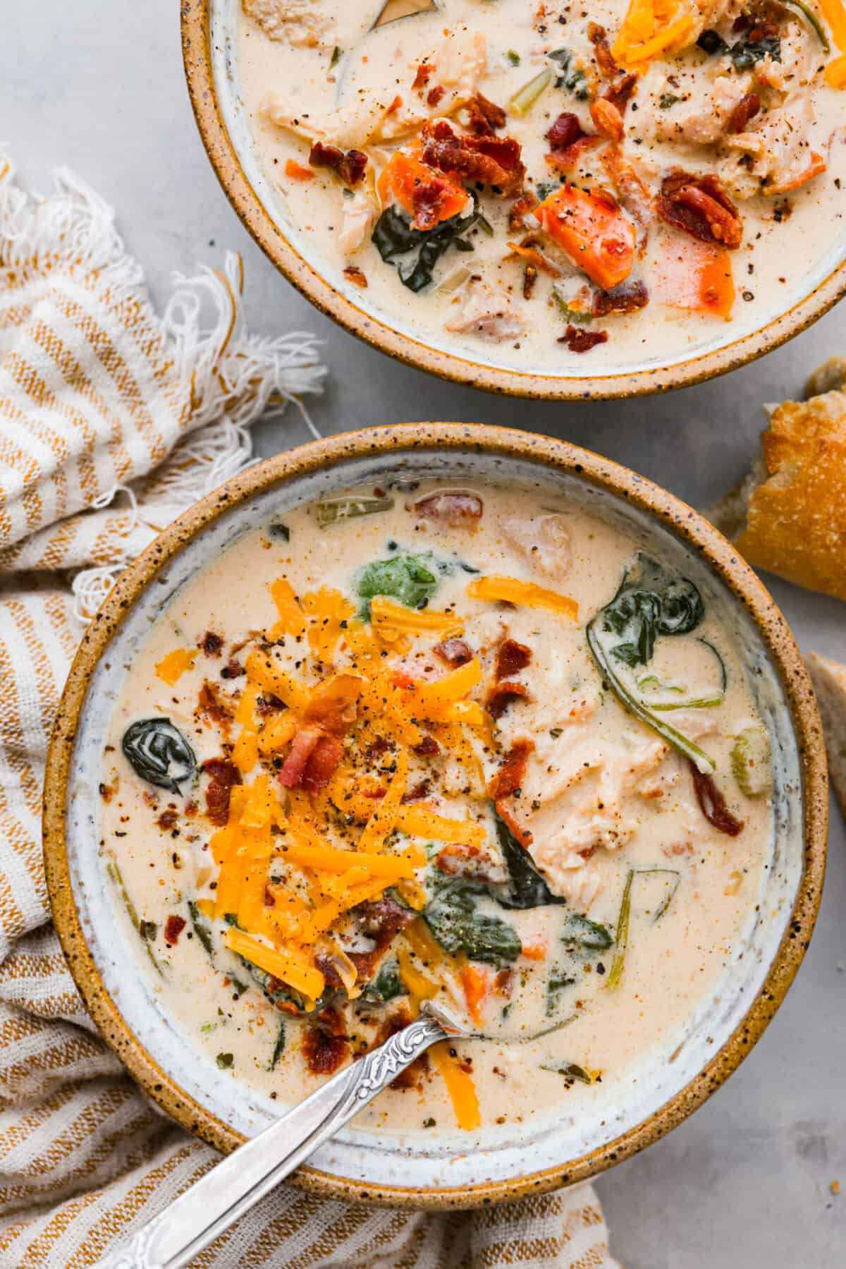 Top view of crack chicken soup in two bowls with shredded cheese on top.