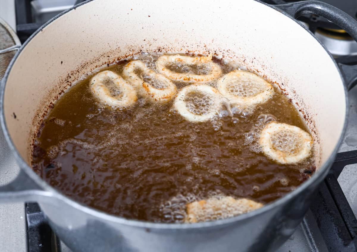 Angle shot of calamari being fried in a pot of oil.