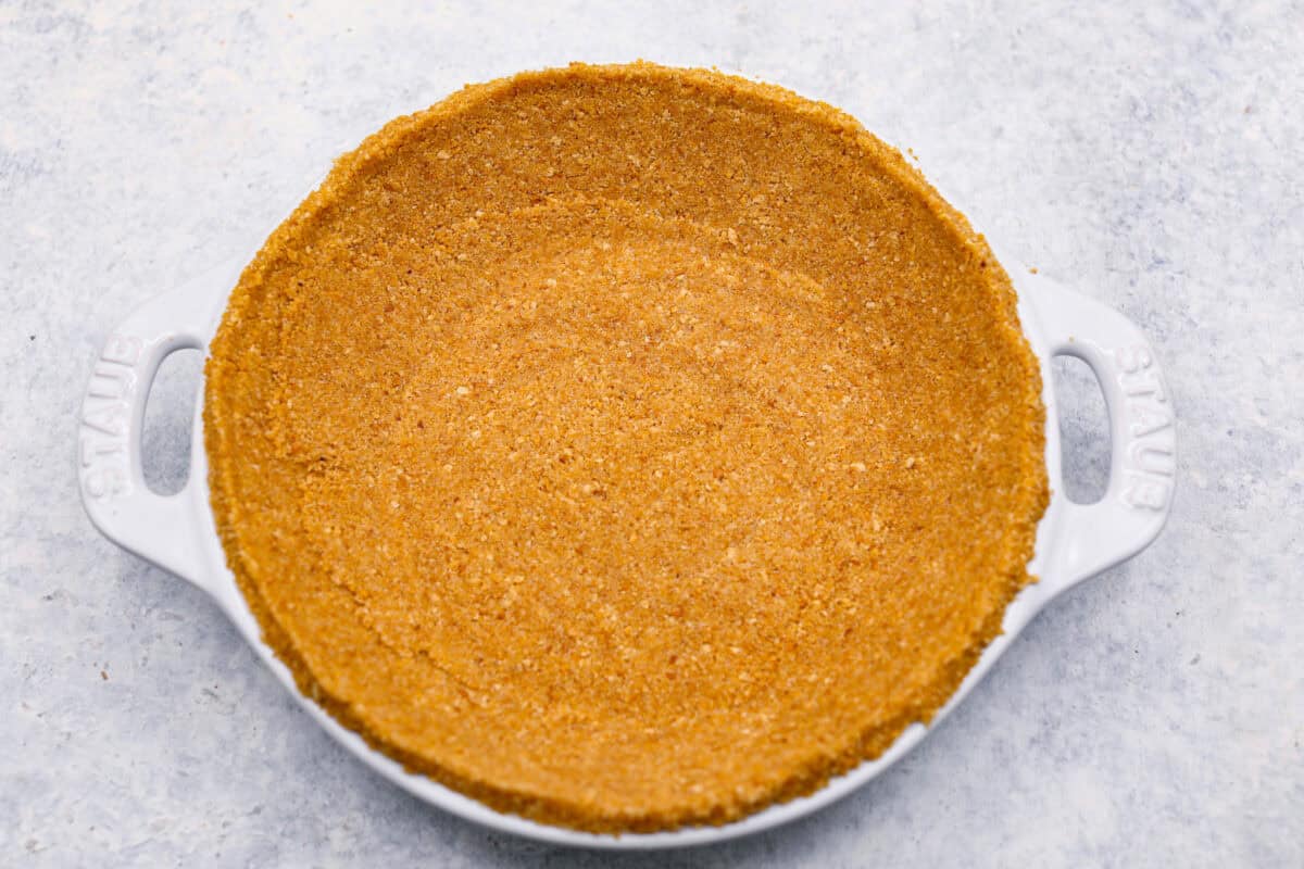 Overhead shot of graham cracker crust mixture pressed flat into a pie pan.