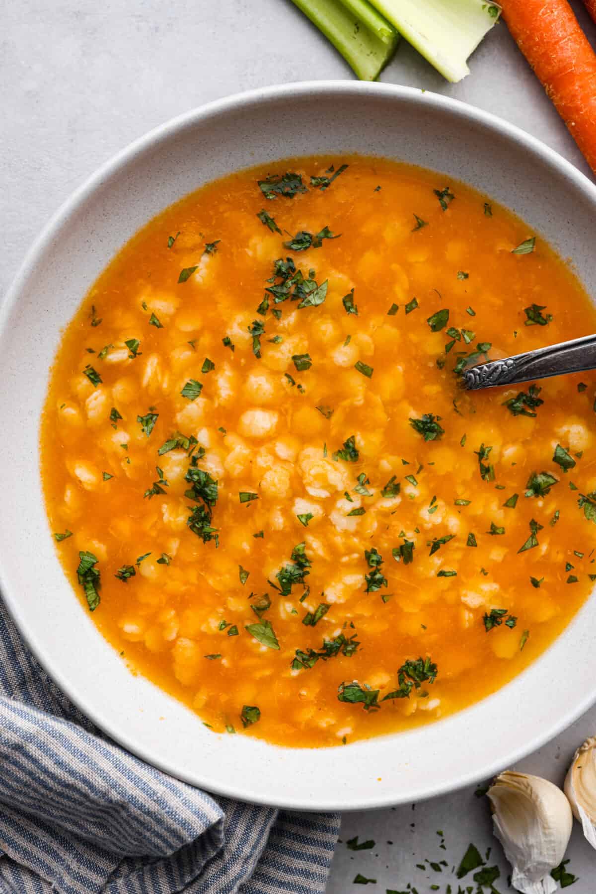 Warm and nourishing Italian Pastina is comfort food at its best! This simple soup recipe is made with chicken broth, vegetables and tiny pasta stars. It's the perfect cozy meal to enjoy when the weather turns cold! A serving of soup in a white bowl.