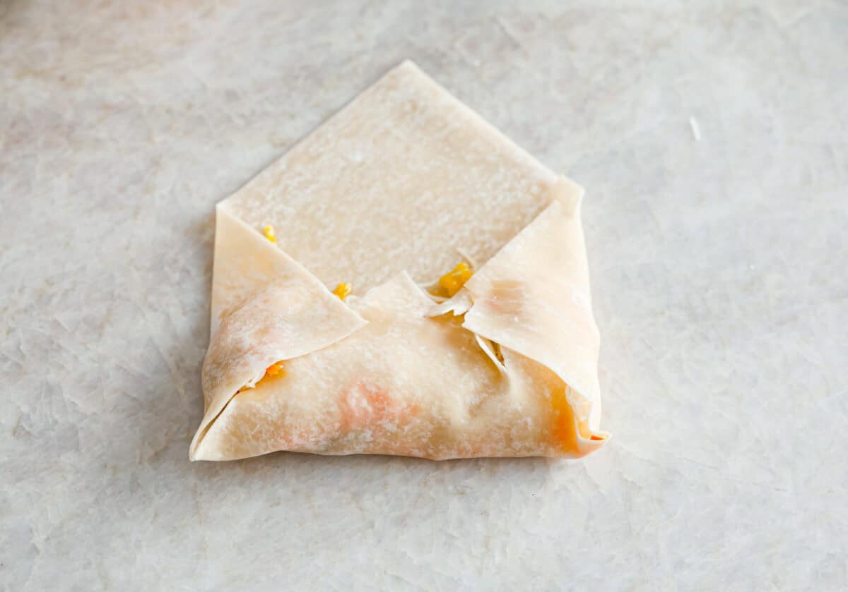 Overhead shot of shrimp egg roll being wrapped in wrapping. 