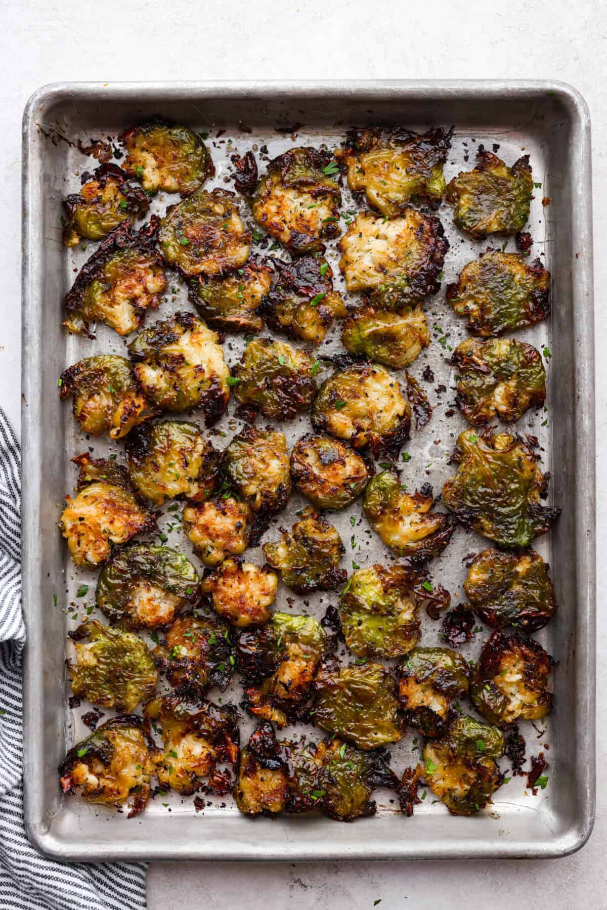 Irresistibly crispy Smashed Brussels Sprouts are simple to make, loaded with delicious flavor, and have the best crunchy texture. These pair well with almost any protein and will definitely upgrade your side dish game! Overhead shot of roasted smashed Brussels sprouts on a baking sheet.