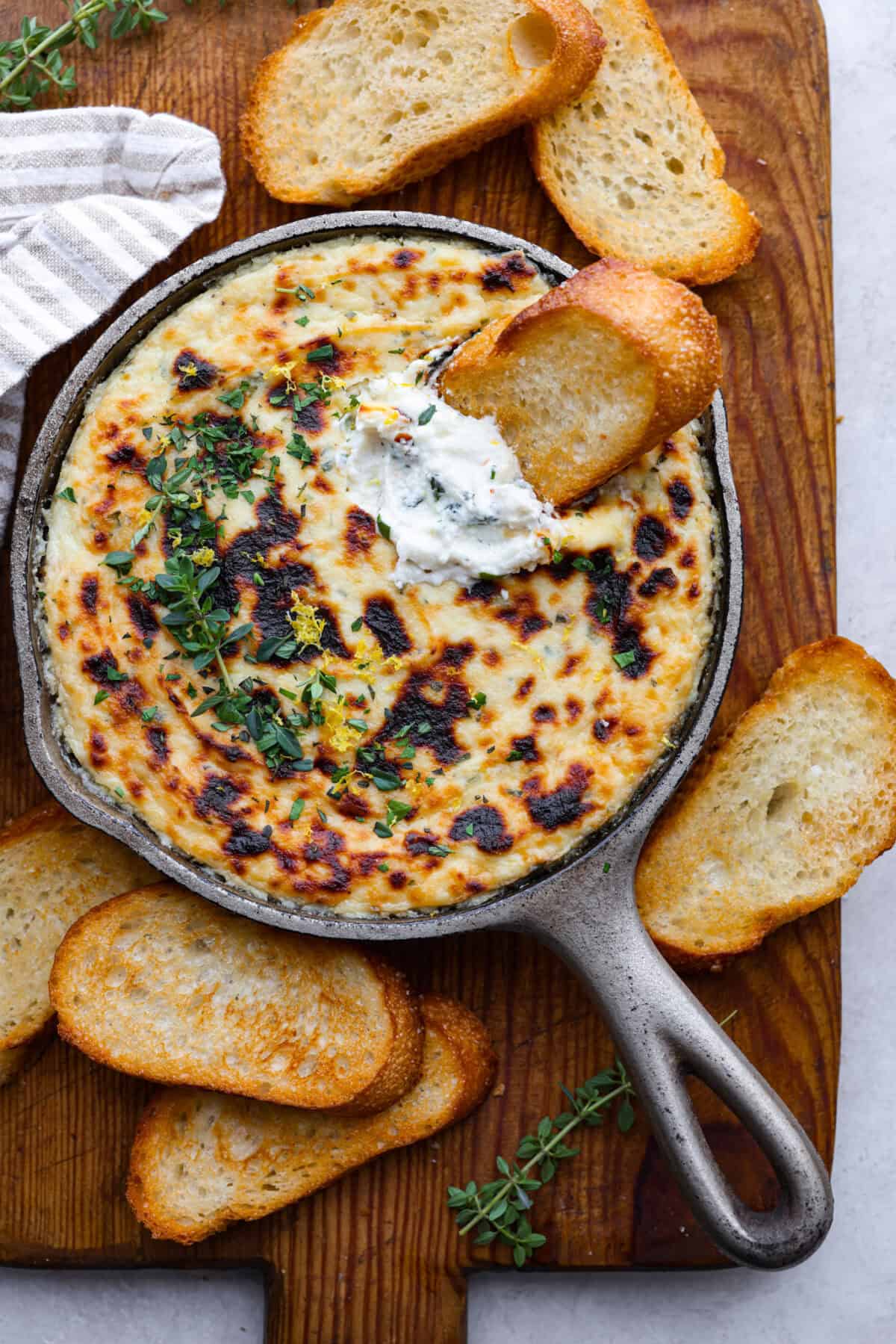 Overhead shot of baked ricotta dip with a crostini in it. 